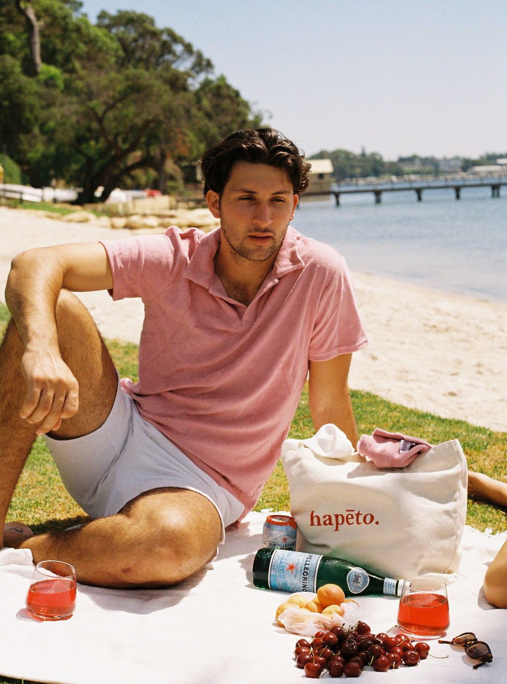 Terry towelling polo shirt in salmon pink, reclining at the beach